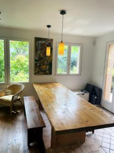 una gran mesa de madera en una habitación con ventanas en La Cour Des Jardins en Neufmoutiers-en-Brie