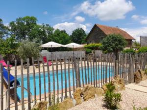 a fence with a swimming pool in front of a house at LeS GITES CAMBOIS in Cambes