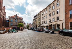 een geplaveide straat met geparkeerde auto's en gebouwen bij Pańska Residence in Gdańsk