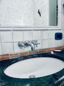 ein Waschbecken mit einem Wasserhahn und einem Spiegel in der Unterkunft Il Bottone al Duomo in Gaeta