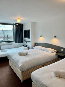 una camera d'albergo con due letti e una finestra di Hounslow Central Hotel a Hounslow