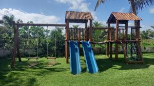 a playground with two swings and a slide at Apartamento Summer ville in Itacimirim