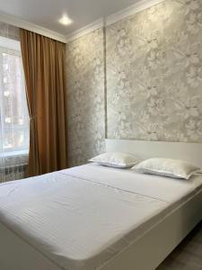 um quarto com uma grande cama branca com flores na parede em Эксклюзив-404 em Astana