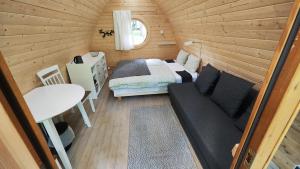 mały pokój z łóżkiem i kanapą w kabinie w obiekcie Meža namiņi Sprīdīši w mieście Tērvete
