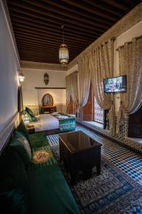 a bedroom with a bed and a tv and a couch at Riad Sidrat Fes in Fès