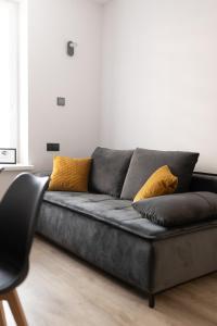 ein schwarzes Sofa im Wohnzimmer mit gelben Kissen in der Unterkunft Apartament Centrum A in Kudowa-Zdrój