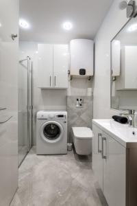 ein weißes Badezimmer mit einer Waschmaschine und einem Waschbecken in der Unterkunft Apartament Centrum A in Kudowa-Zdrój