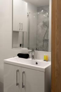 ein weißes Badezimmer mit einem Waschbecken und einem Spiegel in der Unterkunft Apartament Centrum A in Kudowa-Zdrój