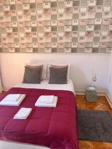 a bedroom with a purple bed with two towels on it at Alvalade II Airport Guest House in Lisbon