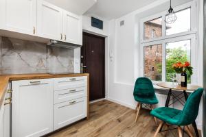 een keuken met witte kasten en een tafel met groene stoelen bij Pańska Residence in Gdańsk +11 foto's