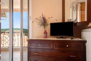 a television on a dresser in a room with a balcony at Lakis Apartment in Meganisi