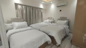 Duas camas num quarto com cobertores brancos e almofadas em التجمع الخامس no Cairo