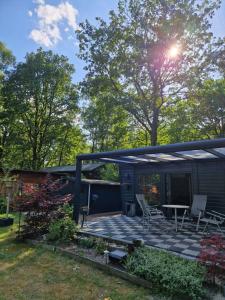 ein kleines Haus mit einer Terrasse in der Unterkunft Riant huisje in bosrijke omgeving op chaletpark Kempenbos in Diessen