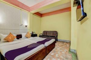 a bedroom with two beds and a chair at SPOT ON Durba 2 in Tezpur