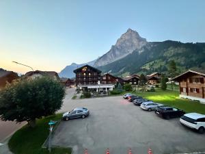 a parking lot with cars parked in front of a mountain at Alpina Appartment 2 in Kandersteg