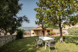 una mesa y sillas bajo un árbol en un patio en B&B Il Chiostro Assisi, en Asís