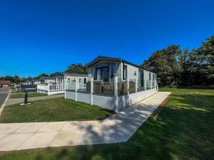 une grande maison avec une terrasse couverte sur une pelouse dans l'établissement Beautiful Caravan With Decking At Carlton Meres Park, Suffolk Ref 60009cl, à Saxmundham