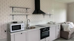 a kitchen with white cabinets and a microwave oven at Crusellska Vandrarhemmet in Strömstad