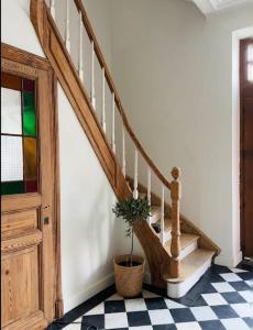 un escalier avec une plante en pot sur un sol en damier dans l'établissement Maison Comtale, à Rochefort