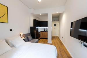een slaapkamer met een wit bed en een flatscreen-tv bij Neos_kosmos_house in Athene