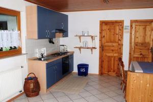 uma cozinha com armários azuis, um lavatório e uma mesa em Ferienwohnungen Röller em Rinnthal
