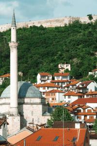 a city with a mosque and a hill with houses at Hotel Centrum Prizren in Prizren