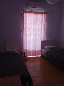- une chambre avec 2 lits et un rideau rouge dans l'établissement Sofias Home, à Nauplie