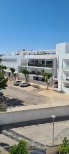 un grand bâtiment blanc avec des voitures garées dans un parking dans l'établissement Tavira Pimpão - Sea View Flat, à Tavira