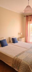 een slaapkamer met 2 bedden en blauwe kussens bij Tavira Pimpão - Sea View Flat in Tavira