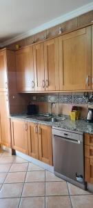 a kitchen with wooden cabinets and a sink and a dishwasher at Tavira Pimpão - Sea View Flat in Tavira