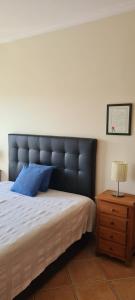 a bed with a black padded headboard next to a table at Tavira Pimpão - Sea View Flat in Tavira