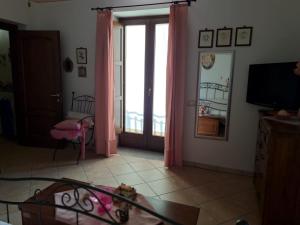 uma sala de estar com cortinas cor-de-rosa e uma televisão em La Casa Di Lidia em Cardile