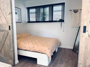a small bedroom with a bed and a window at The Bank's Lodge by ZILT in Limmen