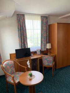 ein Hotelzimmer mit einem Schreibtisch, einem Tisch und Stühlen in der Unterkunft Hotel Garni Eschenbach in Hildburghausen