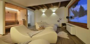 a living room with two white couches and a large tv at Hotel Tambò in Campodolcino