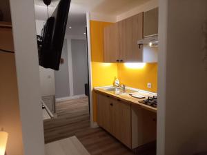 Una cocina con paredes amarillas y un fregadero y un televisor. en La Grelauderie 6, en Saintes 8 fotos más