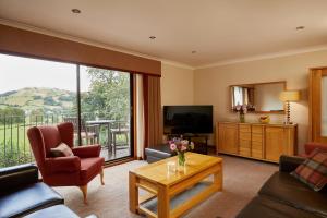 a living room with a couch and a television at Macdonald Plas Talgarth Resort in Pennal