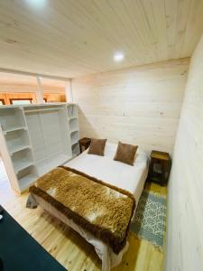 ein Schlafzimmer mit einem Bett in einem Holzzimmer in der Unterkunft forest house - a pasos del mar in Pichilemu