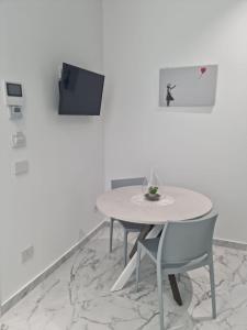 a white table with two chairs and a tv on a wall at Lci Deluxe Rooms in San Cataldo