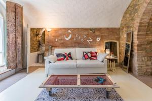Lajatico Domus في لاياتيكو: غرفة معيشة مع أريكة بيضاء وجدار من الطوب