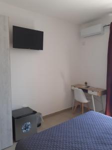 Schlafzimmer mit einem Bett und einem Schreibtisch mit einem TV in der Unterkunft Eliseo's rooms in Triei