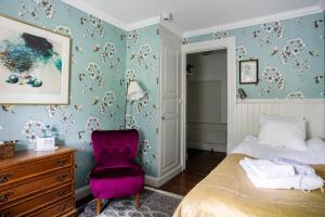 a bedroom with a bed and a purple chair at Grythyttans Gästgivaregård in Grythyttan