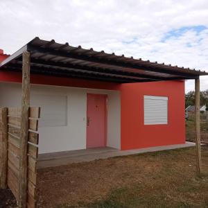 une petite maison rouge et blanche avec une porte rouge dans l'établissement Maria Hospedaje Diario, à Colonia del Sacramento