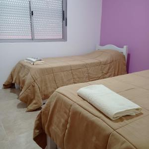 - 2 lits dans une chambre avec des couvertures brunes dans l'établissement Maria Hospedaje Diario, à Colonia del Sacramento