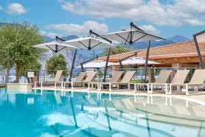 a swimming pool with lounge chairs and umbrellas at June Stay Lake Garda in Brenzone sul Garda
