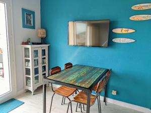 mesa de comedor con sillas y espejo en una pared azul en Cozy Pontaillac, en Vaux-sur-Mer