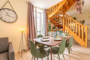 a dining room with a table and chairs and a clock at F3 Duplex lumineux Amazonia Hypercentre Lamartine 203 in Clermont-Ferrand
