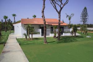 a house with palm trees and a putting green at Alojamiento rural FINCA AZUCENA SUITE in Conil de la Frontera