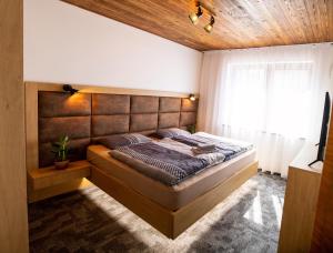 - une chambre avec un grand lit et une tête de lit en bois dans l'établissement Apartmán Hrabušice, à Hrabušice