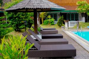 a group of benches with an umbrella next to a pool at Hotel Tulips in Yogyakarta